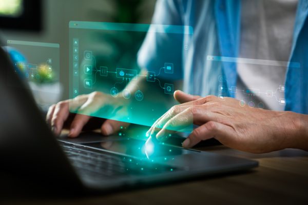 Business professional using laptop with AI workflow automation interface, displaying connected process nodes, data integration icons, and intelligent system orchestration for digital operations